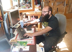 Dustin Flock sitzt am PC in Werkstatt